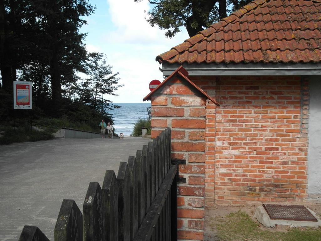 a brick building with a fence next to the ocean at Willa na klifie in Rewal