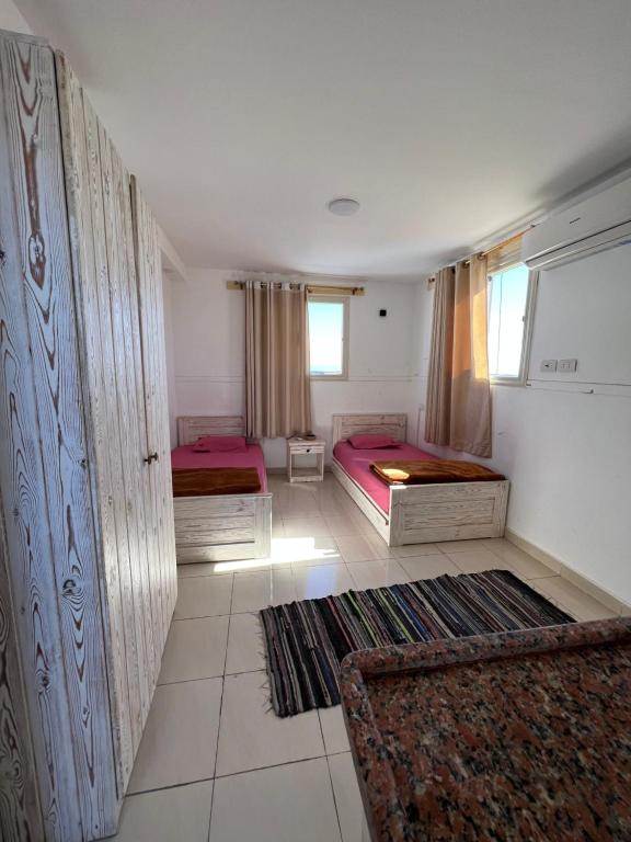 a room with three beds and a window at Ghadghod House in Dahab
