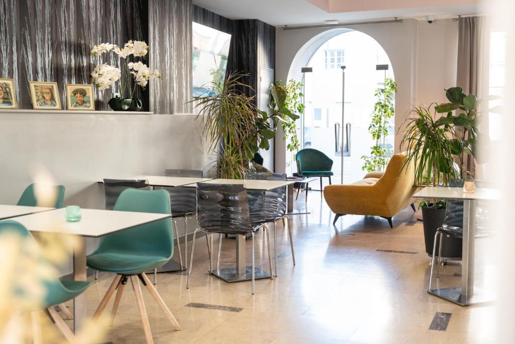 a restaurant with tables and chairs and plants at Grand Hôtel Niort Centre in Niort