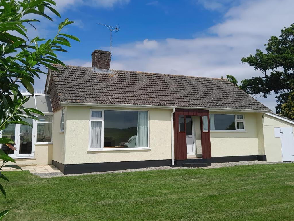 una pequeña casa blanca con un patio de césped en Broadstones, en Bridport