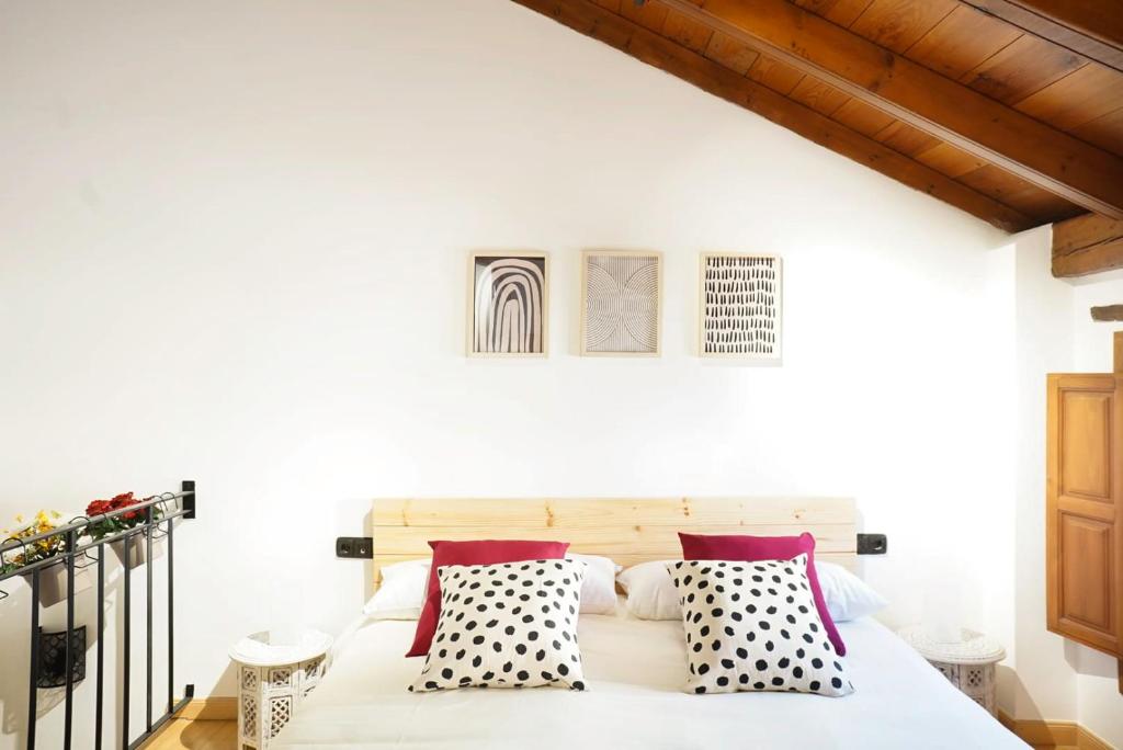 a bedroom with a white bed with black and white pillows at Preciosa casa en el Albaicín in Granada