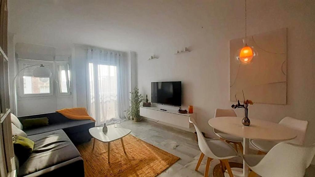 a living room with a couch and a table and a tv at Apartamento Los Naranjos in La Línea de la Concepción