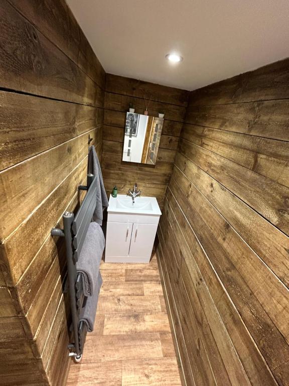 a bathroom with wooden walls and a sink at Aiskew Villa Annex in Bedale