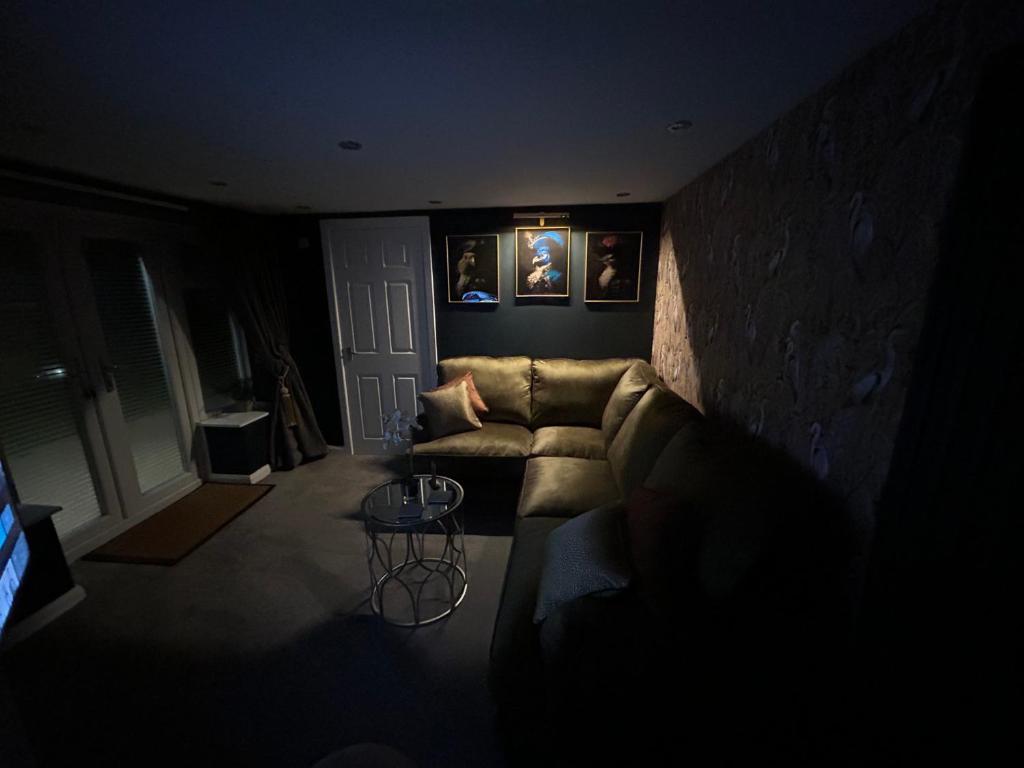 a dark living room with a couch and a table at Aiskew Villa Annex in Bedale