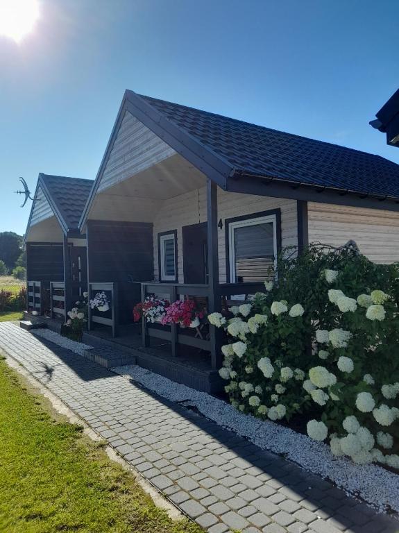 a small house with flowers in front of it at Błękitna Laguna 600m od morza in Rusinowo