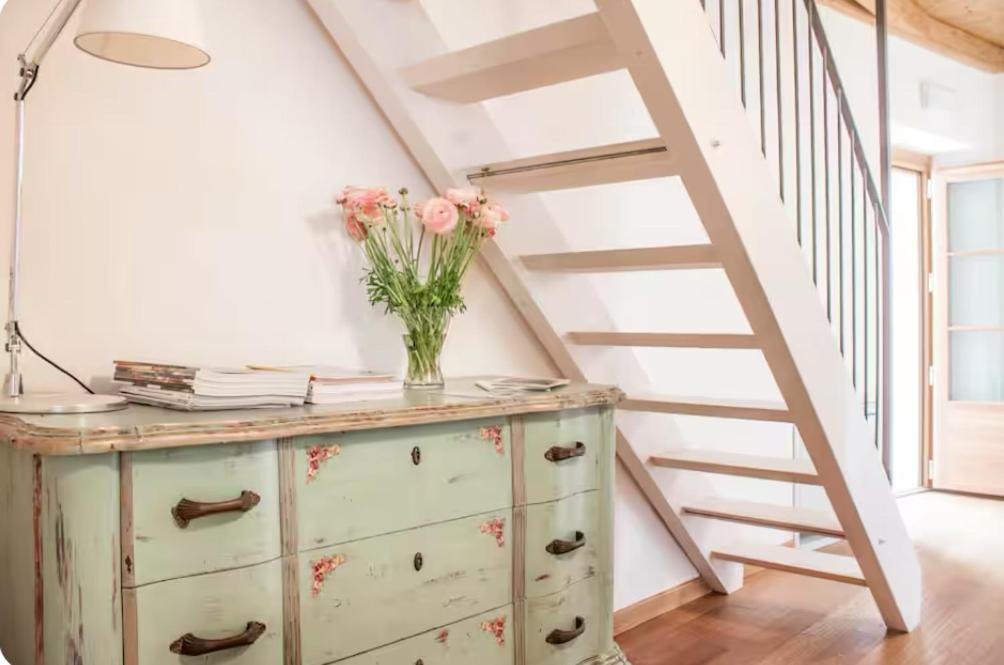 a vase of flowers on a dresser with a staircase at Alla Torre del Barbarossa B&B FORESTERIA in Mandello del Lario