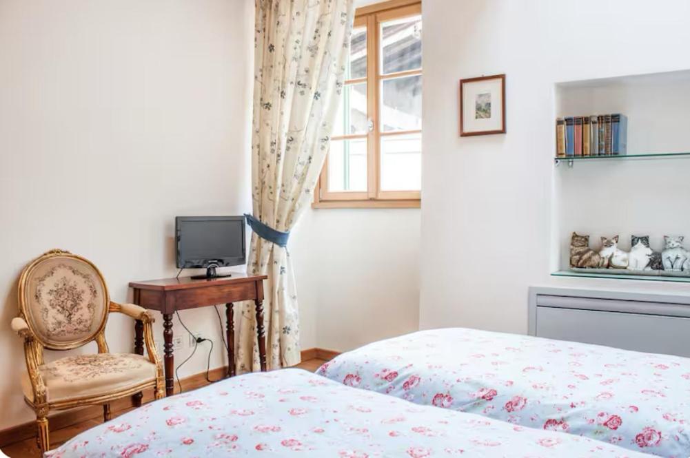 a bedroom with a bed and a chair and a window at Alla Torre del Barbarossa B&B FORESTERIA in Mandello del Lario