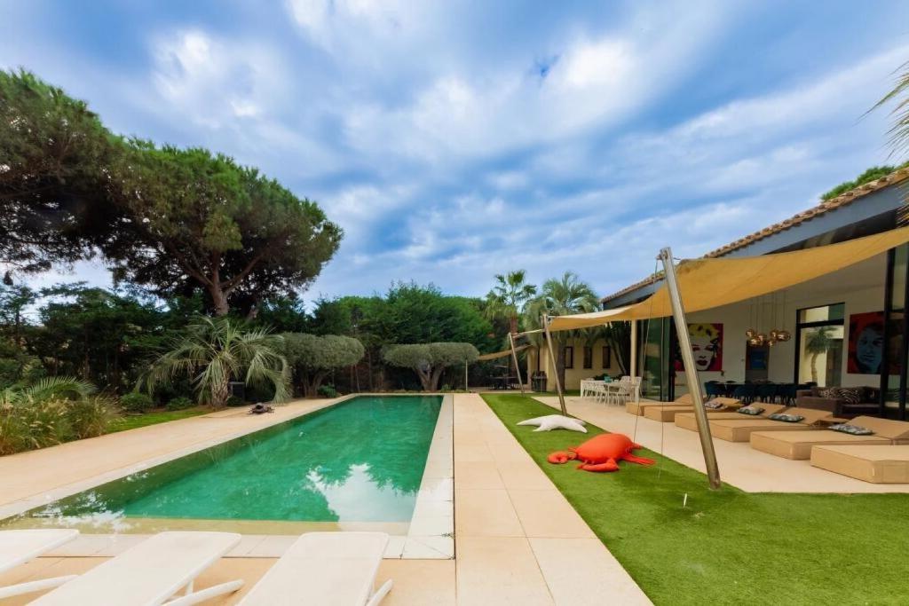 une piscine avec de l'herbe verte et une maison dans l'établissement Superb Villa in Ramatuelle, à Ramatuelle