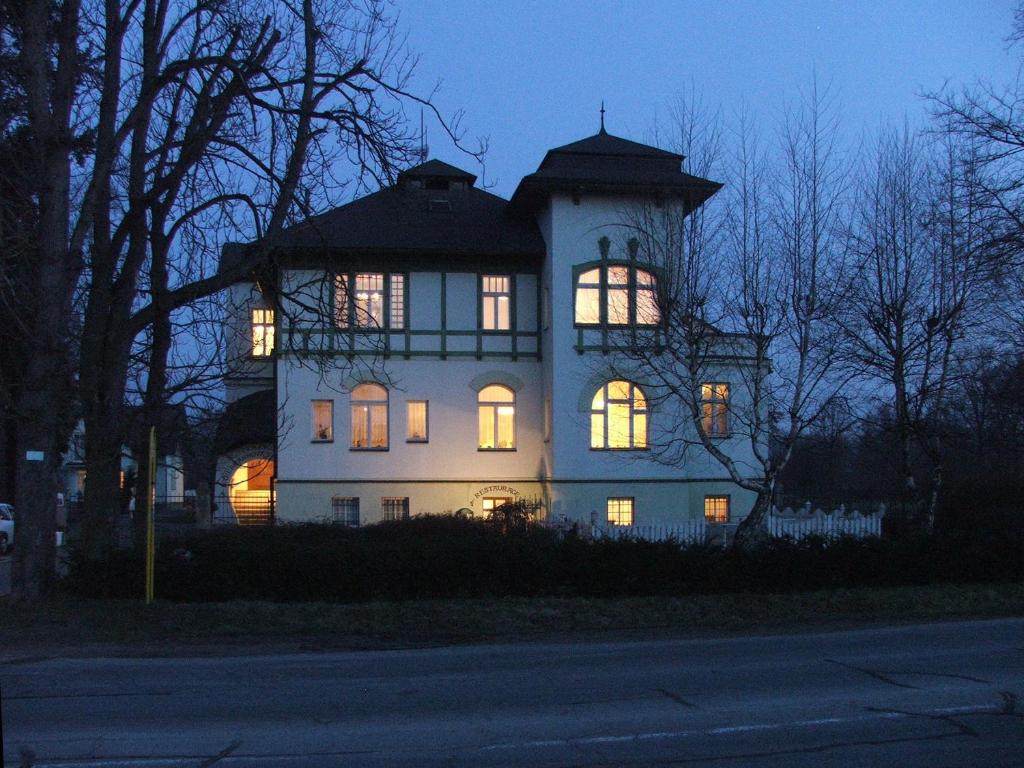 a large white house with its lights on at Pension Habermannova Vila in Bludov