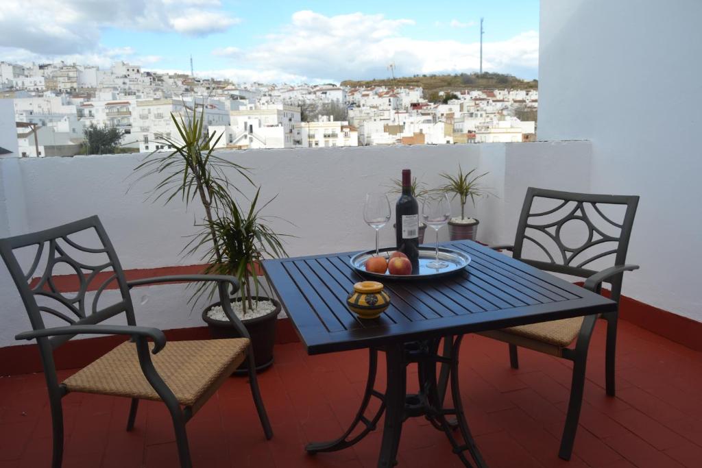 a table with a bottle of wine and two chairs on a balcony at Hotel La Fonda del Califa in Arcos de la Frontera