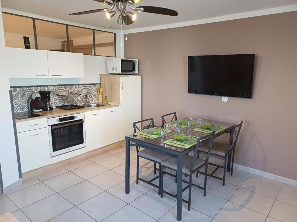 Il comprend une cuisine avec une table et des chaises ainsi qu'une télévision à écran plat. dans l'établissement T2 cosy Pierrefeu du var, à Pierrefeu-du-Var