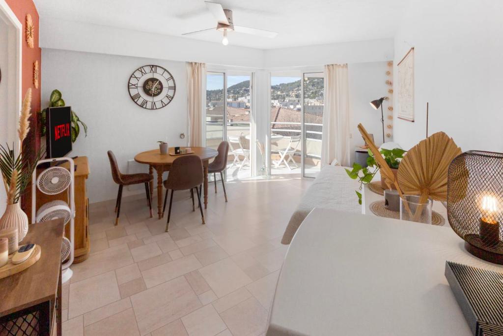 - un salon avec une table et une horloge murale dans l'établissement Les Amandiers - Hypercentre - Terrace - Parking - Cosy, à Vallauris
