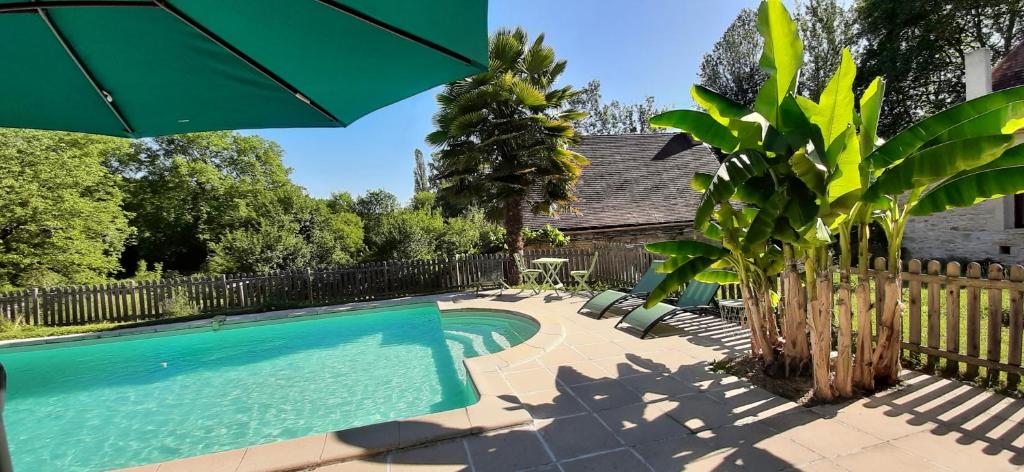 - une piscine avec un parasol à côté d'une clôture dans l'établissement Maison traditionnelle avec piscine, à Gourdon