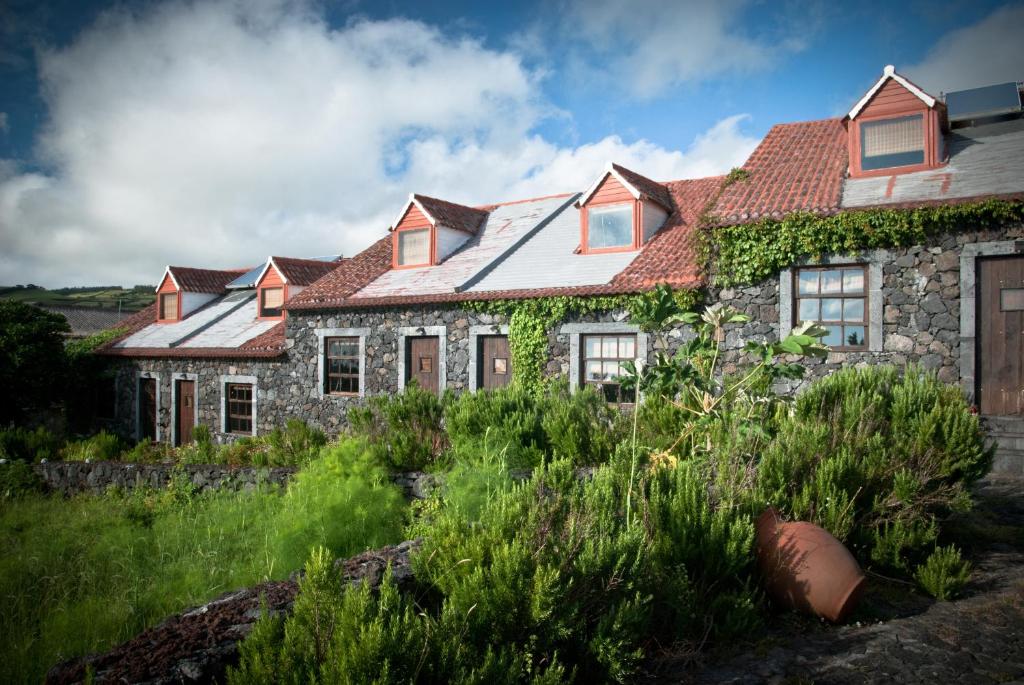 een oud stenen huis met een rood dak bij Hotel os Moinhos in Velas