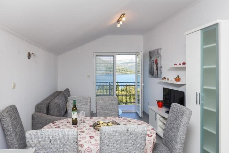 een eetkamer met een tafel en stoelen en een raam bij One Bedroom Apartment with Balcony and Sea View CRVENI in Ston