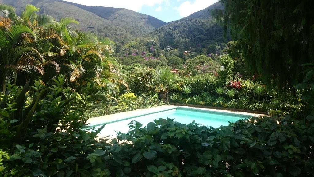 a swimming pool in a garden with mountains in the background at Casa de Araras in Araras Petropolis