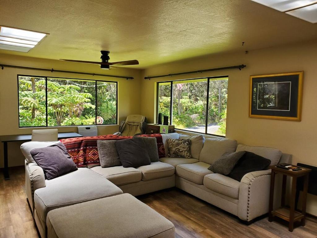 a living room with two couches and two windows at ʻOhiʻa Lehua Forest House in Volcano