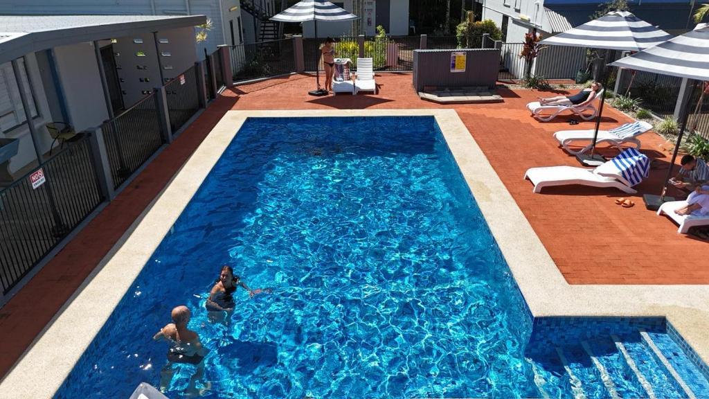 a swimming pool with two people in the water at Caravella Backpackers in Cairns