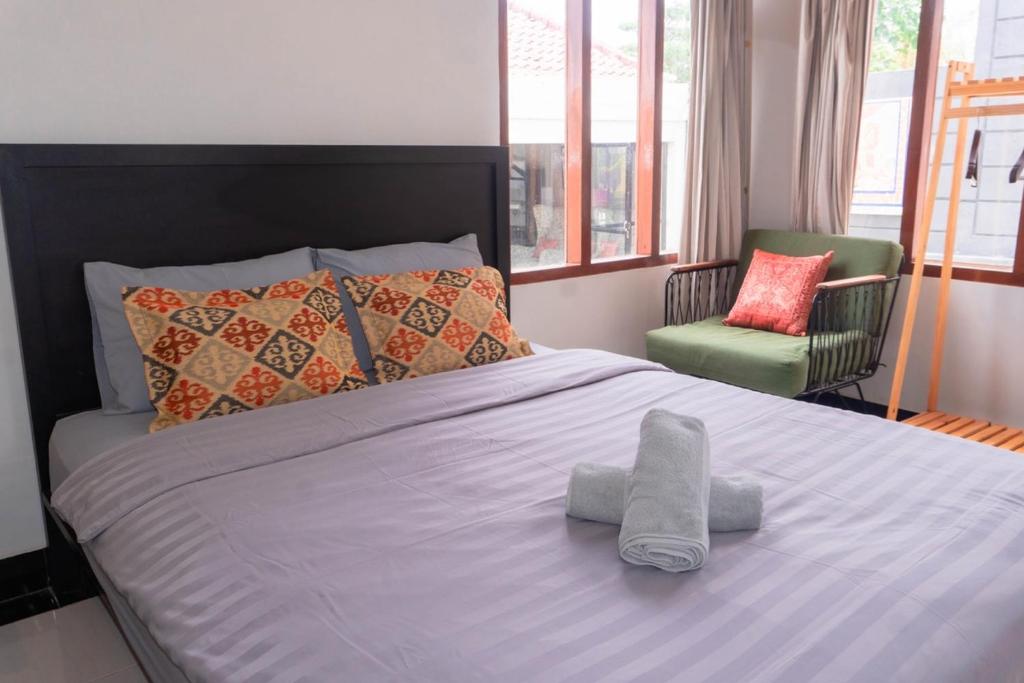a bedroom with a large bed and a chair at Aurora Holiday House Kintamani in Kintamani