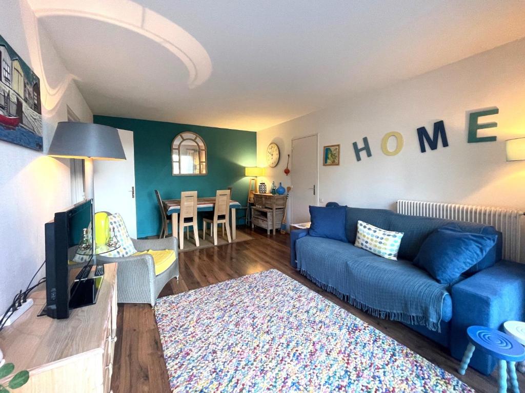 un salon avec un canapé bleu et une salle à manger dans l'établissement Arcachon Centre - T2 Confortable avec Balcon et Parking Privé - FR-1-420-156, à Arcachon