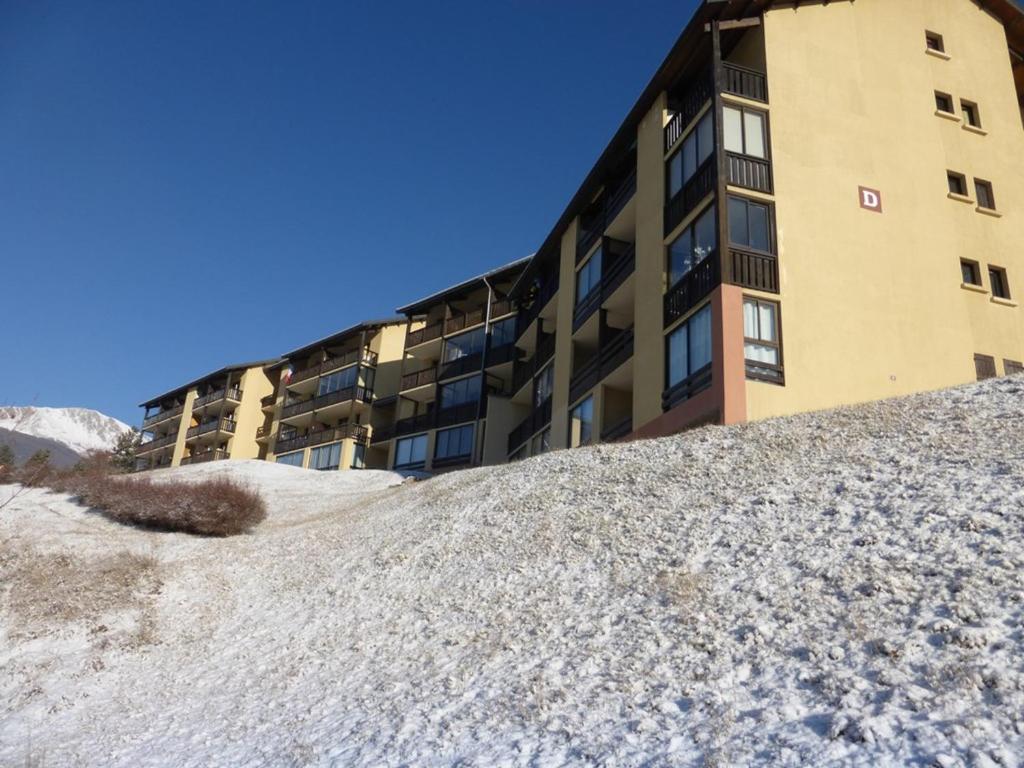 un bâtiment avec une pile de neige devant lui dans l'établissement Studette 2 pers. avec box à skis, Barcelonnette - FR-1-804-52, à Barcelonnette