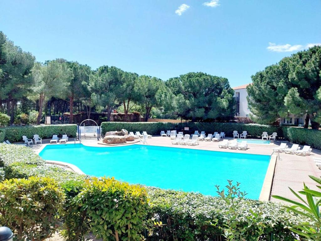 une grande piscine bleue avec des chaises et des arbres blancs dans l'établissement Appartement 2 pièces en duplex avec terrasse et piscine à Balaruc-les-Bains - FR-1-553-301, à Balaruc-les-Bains