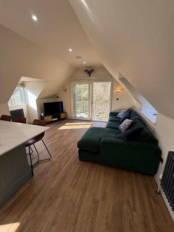 a living room with a green couch and a tv at Dukes Flat in Ampney Saint Peter