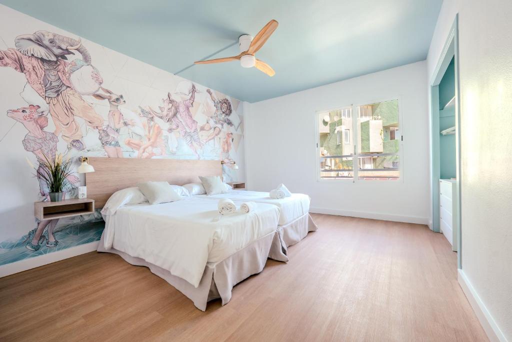 two beds in a bedroom with a mural on the wall at Nura Houses Magaluf Beach in Magaluf