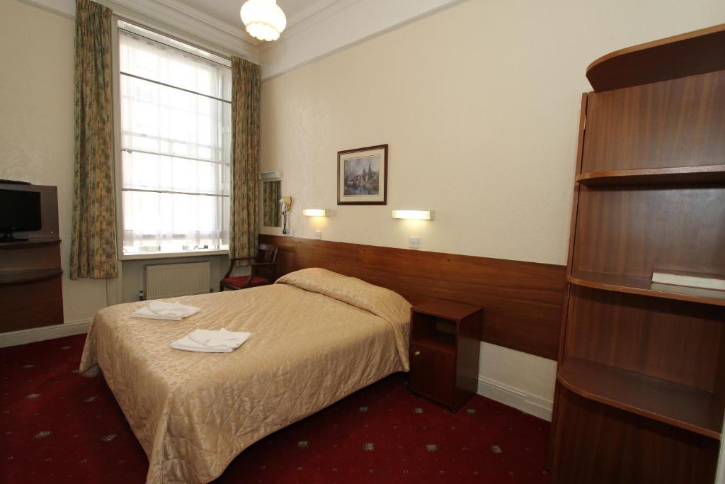 a hotel room with a bed and a window at Ridgemount Hotel in London