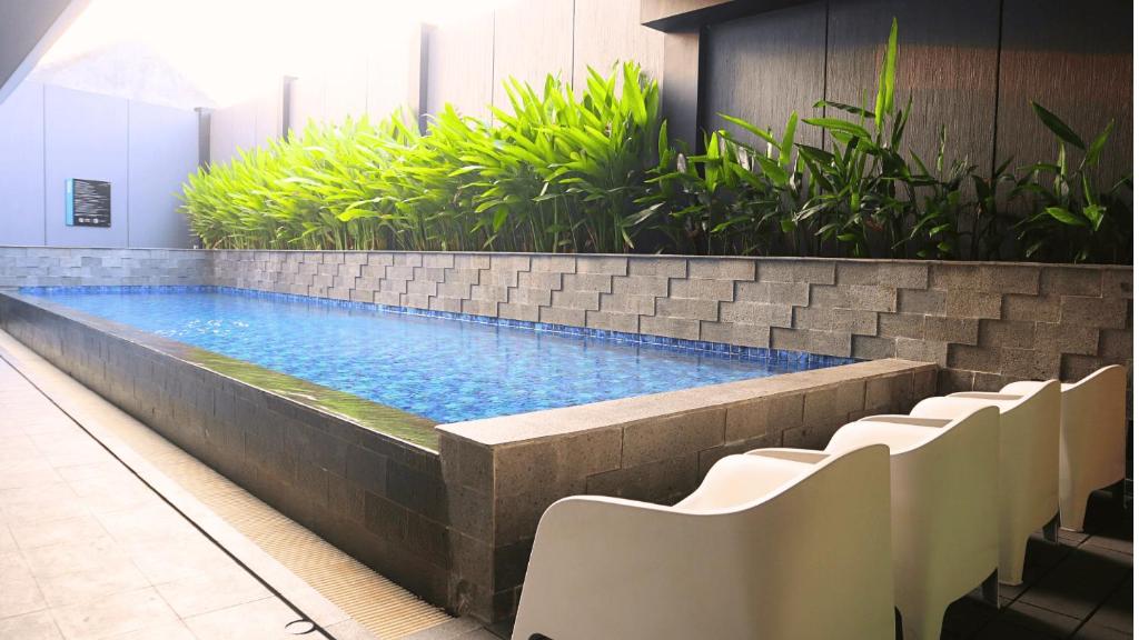una piscina nella hall con sedie e piante di VNC Alam Sutera Hotel Powered by Archipelago a Dongkal