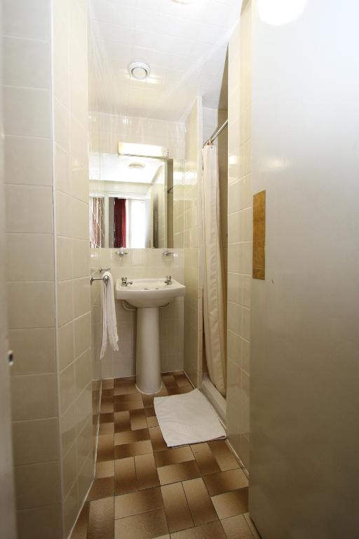 a white bathroom with a sink and a mirror at Ridgemount Hotel in London