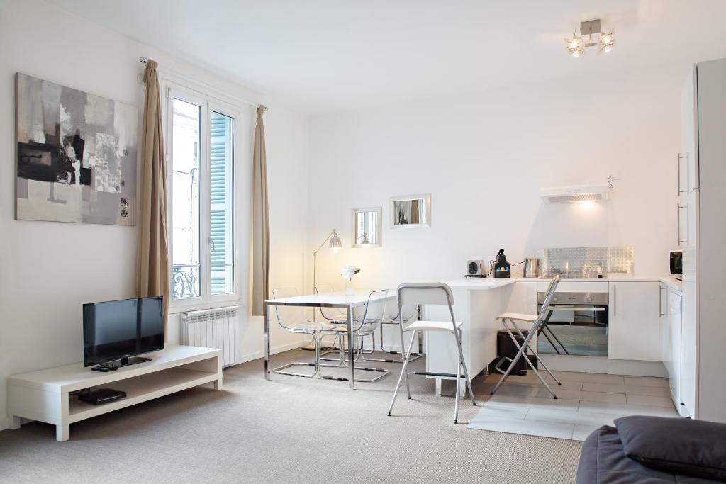 a white living room with a table and a kitchen at Charmant 2 Pièces in Honfleur