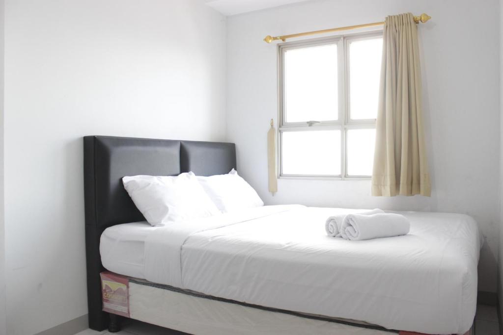 a bedroom with a large white bed with a window at Comfy 2BR Apartment at Mekarwangi Square Cibaduyut By Travelio in Bandung