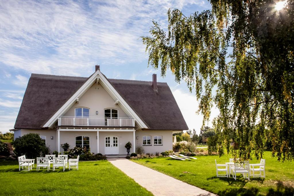 ein weißes Haus mit weißen Stühlen auf dem Rasen in der Unterkunft Lerchenhof Reestow - Ruhige Premium Apartments & Sauna in Reestow