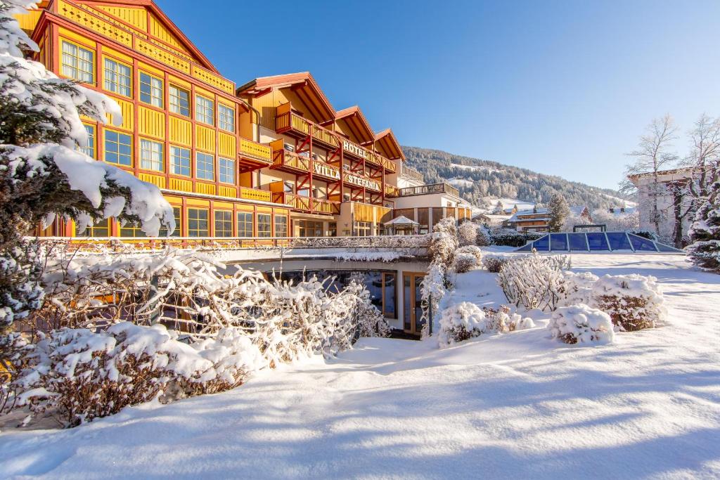 a large yellow building with snow on the ground at Hotel Villa Stefania in San Candido