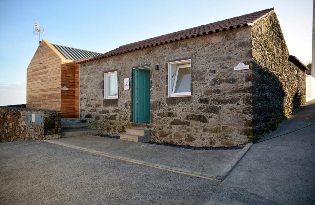 una casa de piedra con puerta verde y aphalt en Aldeia do Priolo, en Nordeste