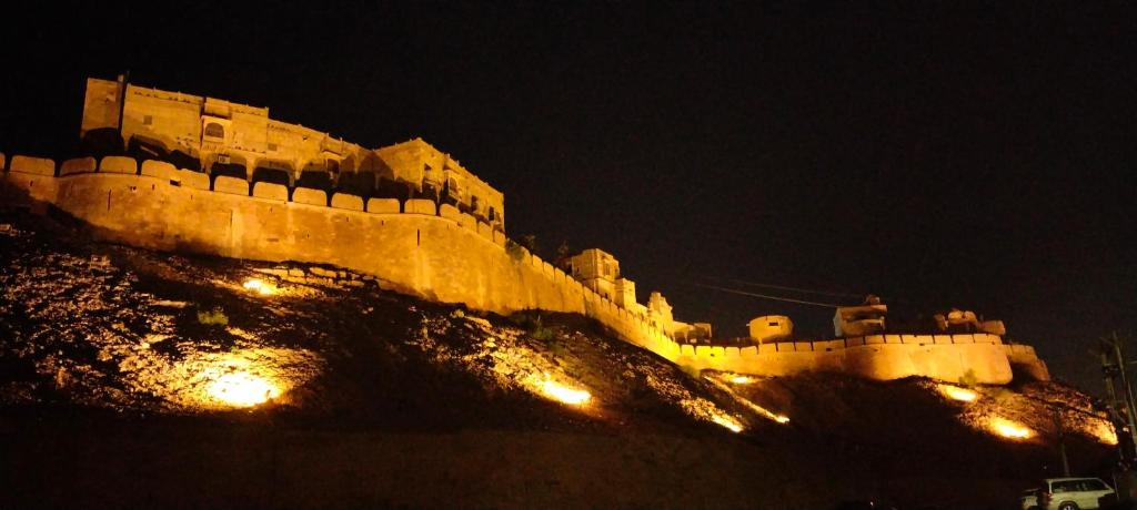 un château assis au sommet d'une colline la nuit dans l'établissement The Desert Prince, à Jaisalmer