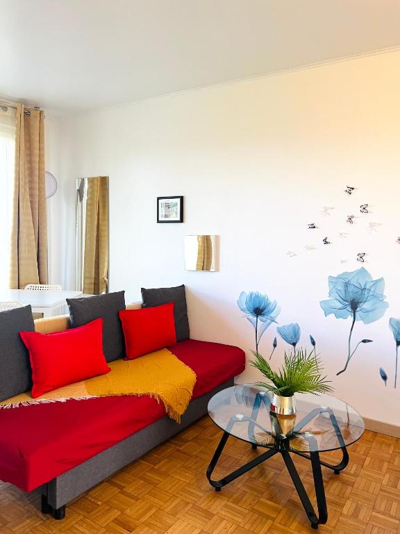 - un salon avec un canapé et des oreillers rouges et jaunes dans l'établissement Rosny Sous Bois très charmant l'appartement en plein centre ville et verdure, à Rosny-sous-Bois