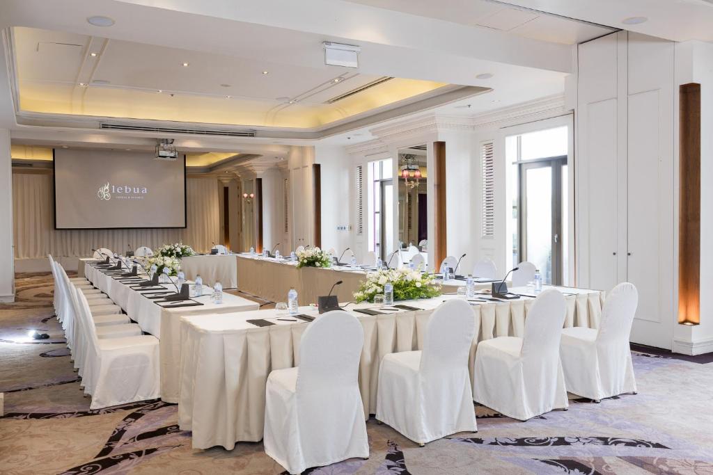 A bright conference room with a long meeting table facing a presentation screen.