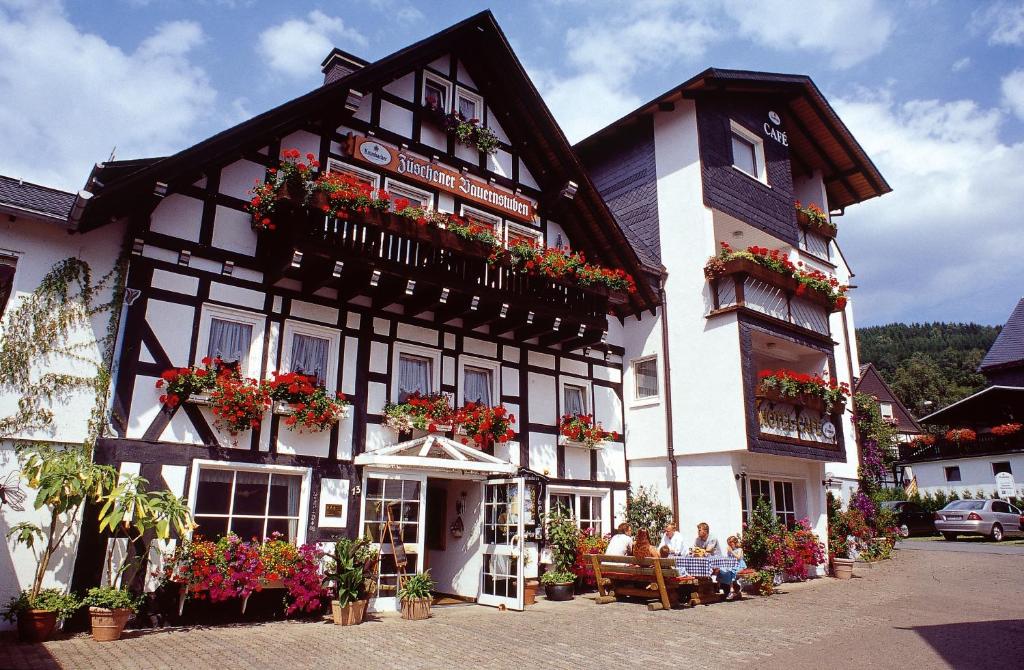 a black and white building with flowers in the windows at Pension Zueschener Bauernstuben in Winterberg