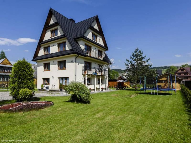 a large house with a black roof on a green yard at Kwatery u Malika-blisko do term Szaflary i Gorący Potok-rabaty in Szaflary