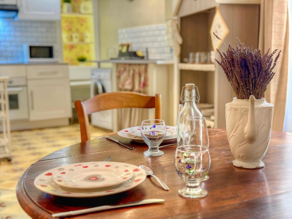 a wooden table with a plate and a bottle and glasses at Appartement provençal, Aups in Aups
