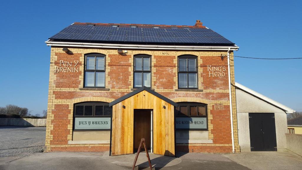 um edifício de tijolos com painéis solares no telhado em Kings Head em Capel Hendre