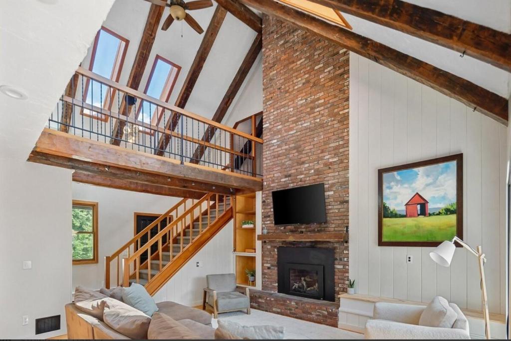 a living room with a staircase and a fireplace at Spacious Mountain Retreat set on 7 acres & Pond in Stowe