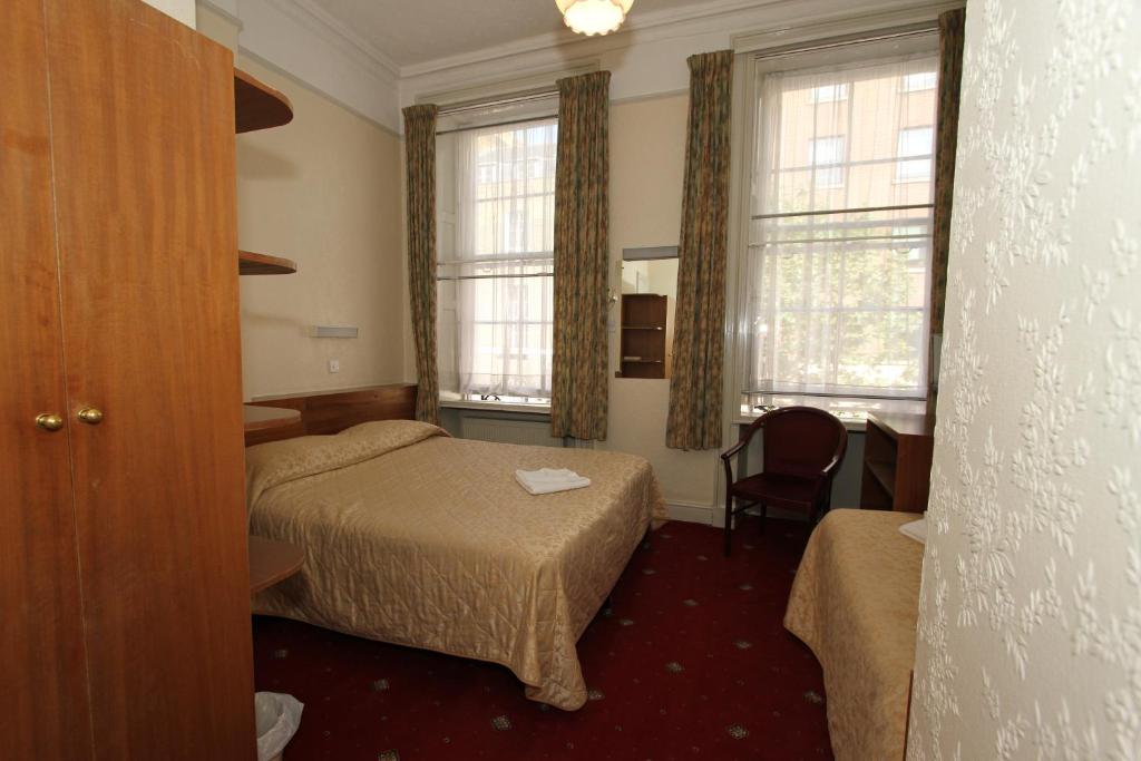 a hotel room with two beds and a chair at Ridgemount Hotel in London