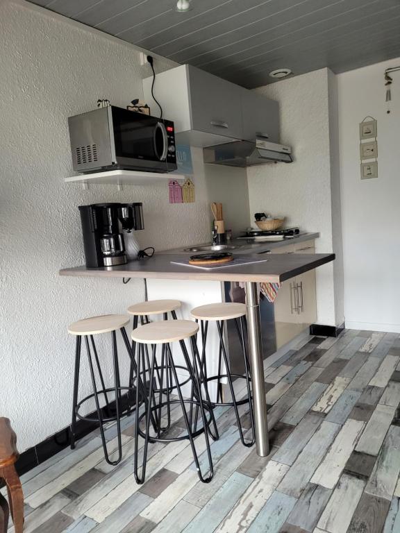 une cuisine avec un comptoir avec des tabourets et un four micro-ondes dans l'établissement Logement calme proche du Touquet, à Cucq