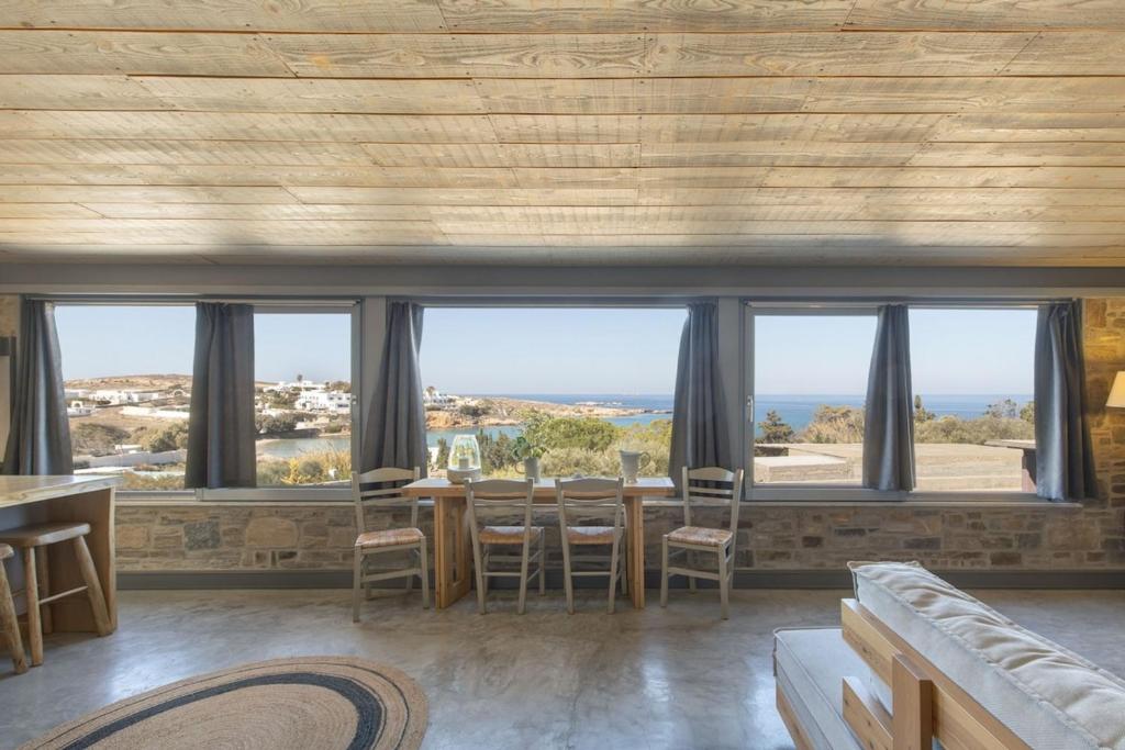 a room with a table and chairs and windows at Vitamine Sea House - Island Living Paros in Parasporos