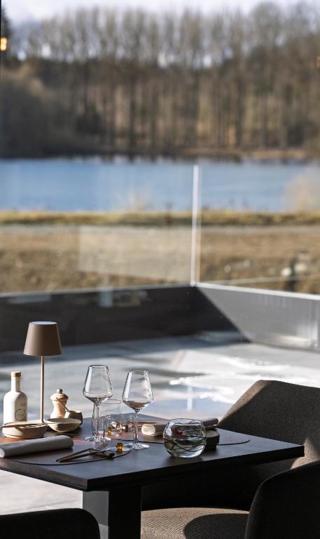 a table with wine glasses and a view of a lake at Anatura Luxembourg in Weiswampach
