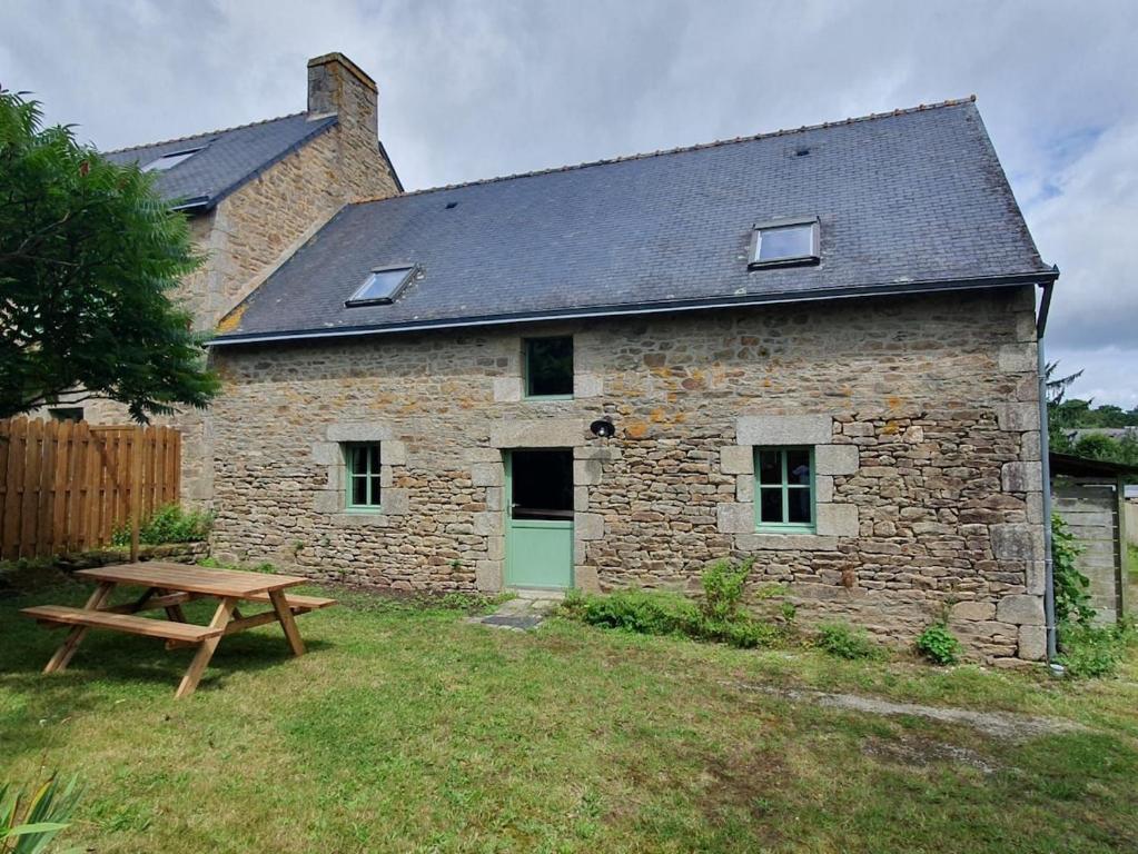 - un bâtiment en pierre avec une table de pique-nique devant dans l'établissement Charming Breton farmhouse, à Rédené