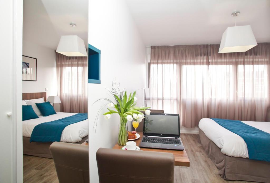 une chambre d'hôtel avec 2 lits et un ordinateur portable sur un bureau dans l'établissement Odalys City Amiens Blamont, à Amiens